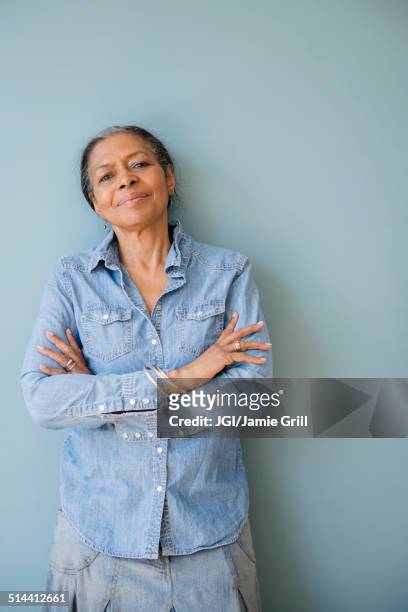 mixed race woman standing with arms crossed - dreiviertelansicht stock-fotos und bilder