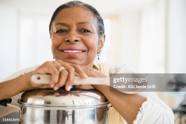 mixed race woman cooking in kitchen - woman cooking pan stock pictures, royalty-free photos & images