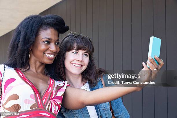 women taking cell phone picture together outdoors - profile shoot of founder of crossbow miles srishti bakshi stockfoto's en -beelden