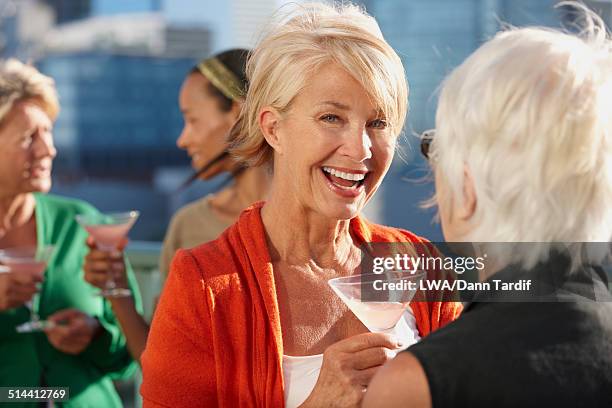 women having drinks together on urban rooftop - 60s cocktail party stock-fotos und bilder