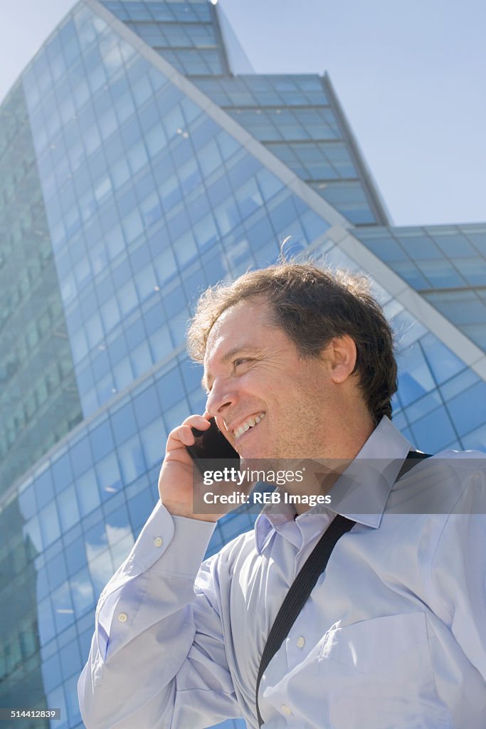 Hispanic businessman talking on cell phone on city street