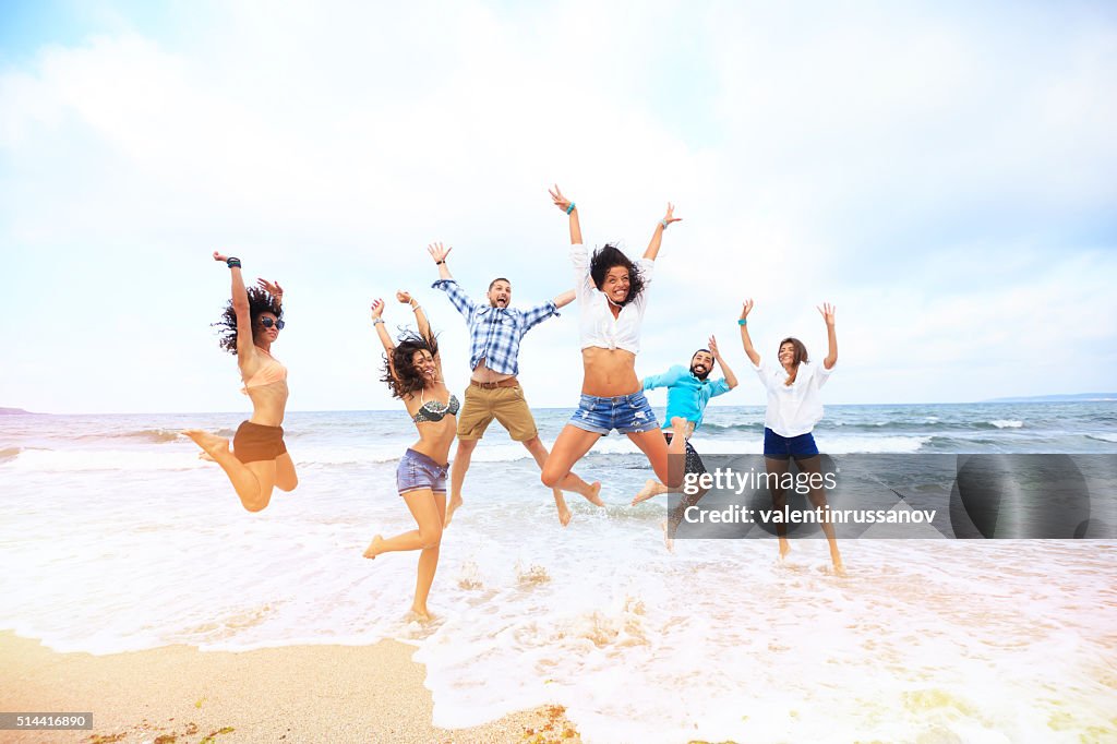 Glückliche Freunde springen über dem Wasser