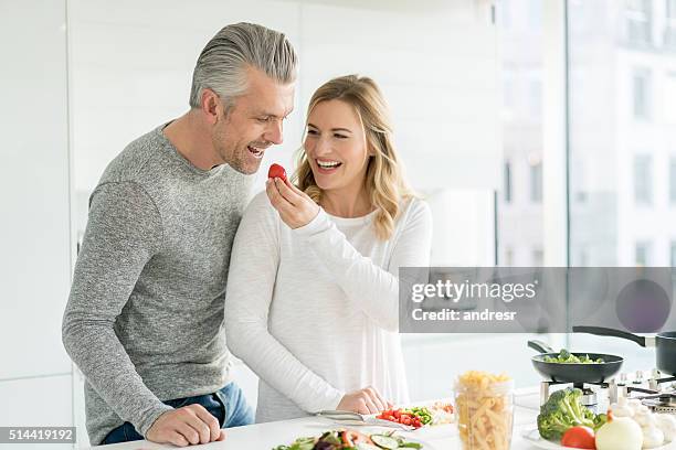 幸せなカップル一緒にホームクッキング - middle aged couple cooking ストックフォトと画像