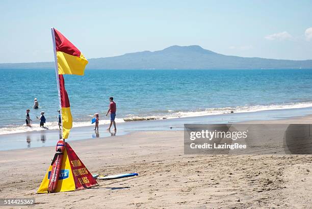 surf life saving new zealand (slsnz) flags on auckland beach - north shore city stock pictures, royalty-free photos & images