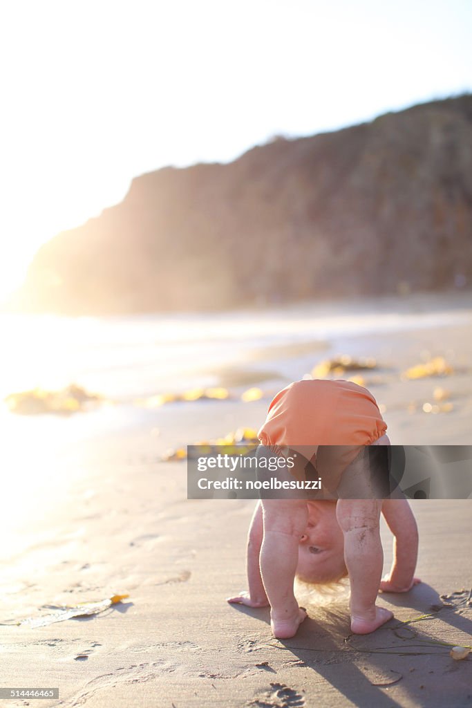 Toddler bending over on beach