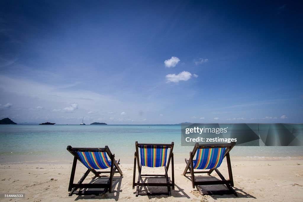 Three deck chairs in a row on the beach, Phuket, Thailand