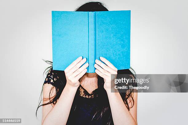 woman hiding behind book - book cover foto e immagini stock