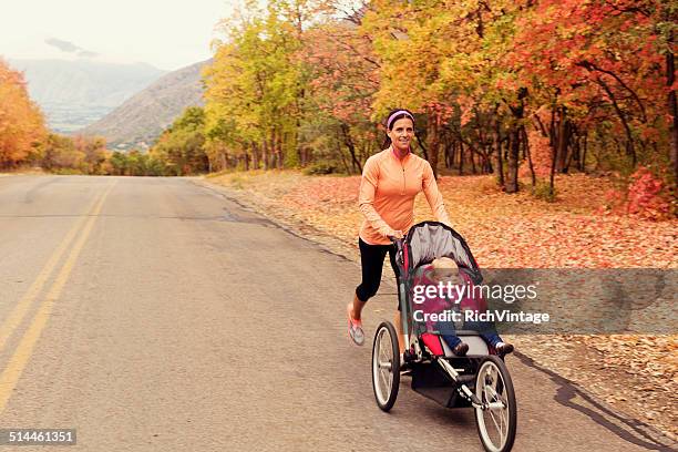 mother running with daugter in jogging stroller - three wheeled pushchair stock pictures, royalty-free photos & images