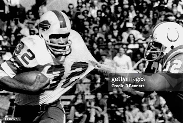 Simpson of the Buffalo Bills runs with the ball as Mike Curtis of the Baltimore Colts goes for the tackle on October 12, 1975 at Memorial Stadium in...