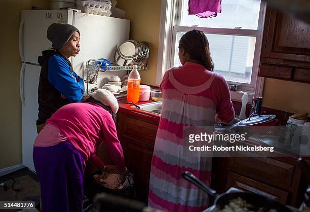 As she washes dishes in her kitchen, Hema Gurung talks with her brother-in-law, Dambar Gurung and mother-in-law, Man Maya Gurung, Burlington,...