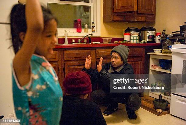 In her family's kitchen, Deeya Gurung walks past her mother, Hema and uncle, Dambar, Burlington, Vermont, January 5, 2016. Members of the extended...