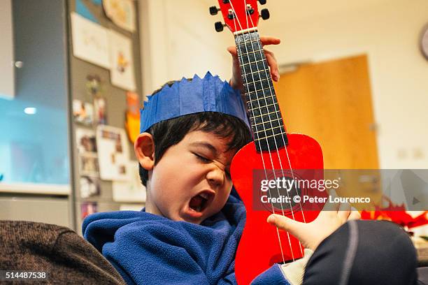 young boy playing a small guitar - kids instruments fotografías e imágenes de stock