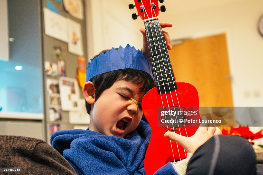 Young boy playing a small guitar