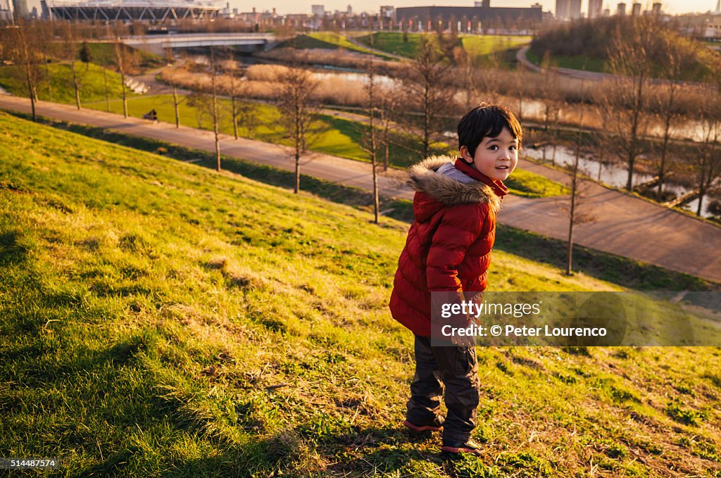 Young boy stood at the top of a grass hill