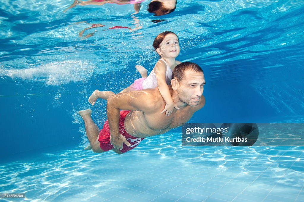 Father and daughter diving in the pool