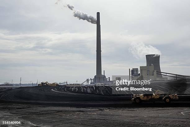 Scrubber stack stands as a scraper pan smooths out a pile of coal at the American Electric Power Mountaineer coal plant in Letart, West Virginia,...