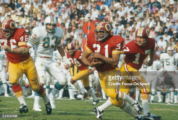 Quarterback Billy Kilmer of the Washington Redskins hands the ball off to teammate Charlie Harraway during Super Bowl VIII against the Miami Dolphins...