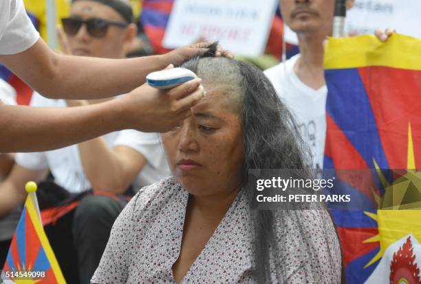 Tibetan protester shaves the head of a Tibetan woman during a rally to mark the 57th Tibetan National Uprising Day at Martin Place in Sydney on March...