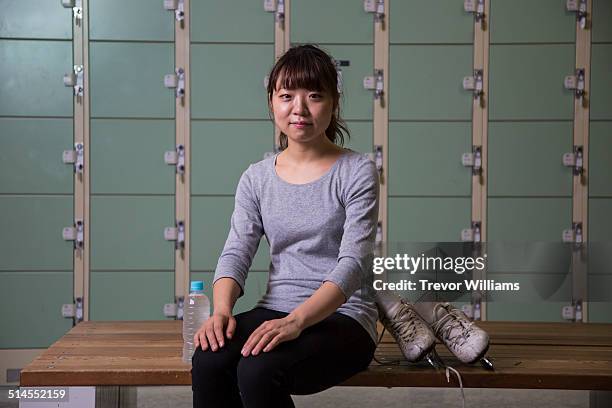 a woman sitting in the locker room with ice skates - hand on knee stock pictures, royalty-free photos & images