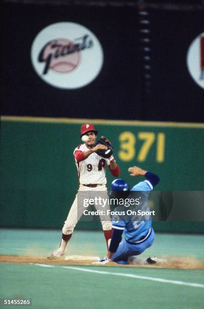 Manny Trillo of the Philadelphia Phillies guards 2nd base and throws to first while Amos Otis of Kansas City Royals slides in during the World Series...