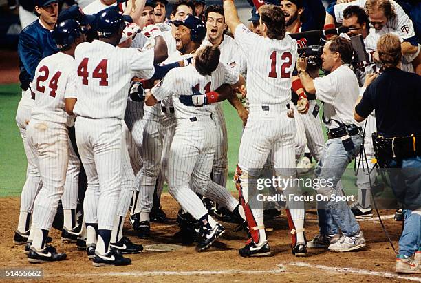 Kirby Puckett of the Minnesota Twins is mobbed by his teammates at home plate after hitting the game winning home run against the Atlanta Braves in...