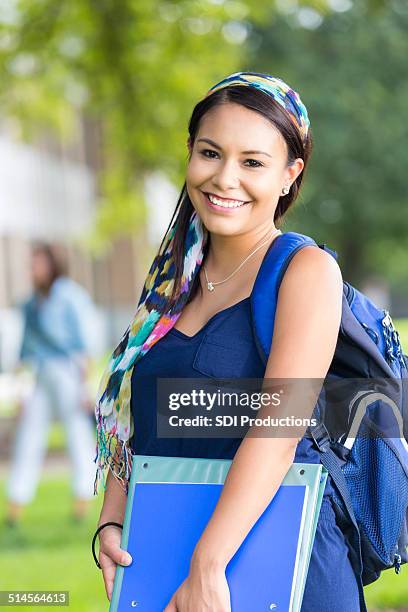 beautiful hispanic college student holding books on campus - college visit stock pictures, royalty-free photos & images