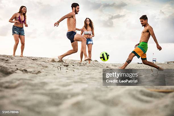 friends playing soccer during vacations on the beach - beach football stock pictures, royalty-free photos & images