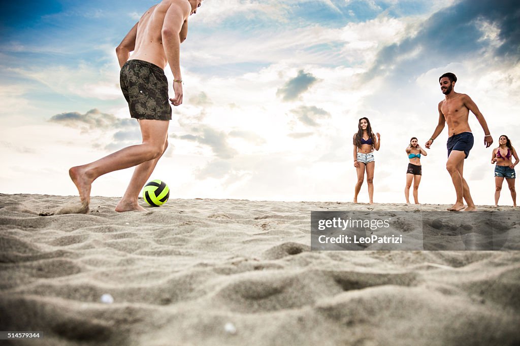 Friends playing soccer during vacations on the beach