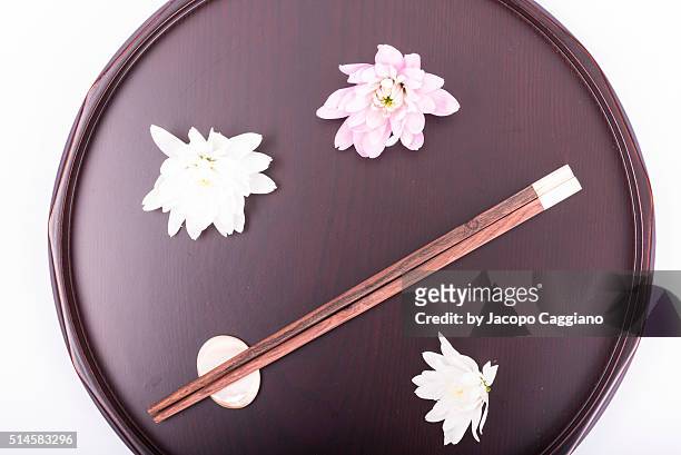 japanese composition with chopsticks and flowers on a serving plate - jacopo caggiano stockfoto's en -beelden