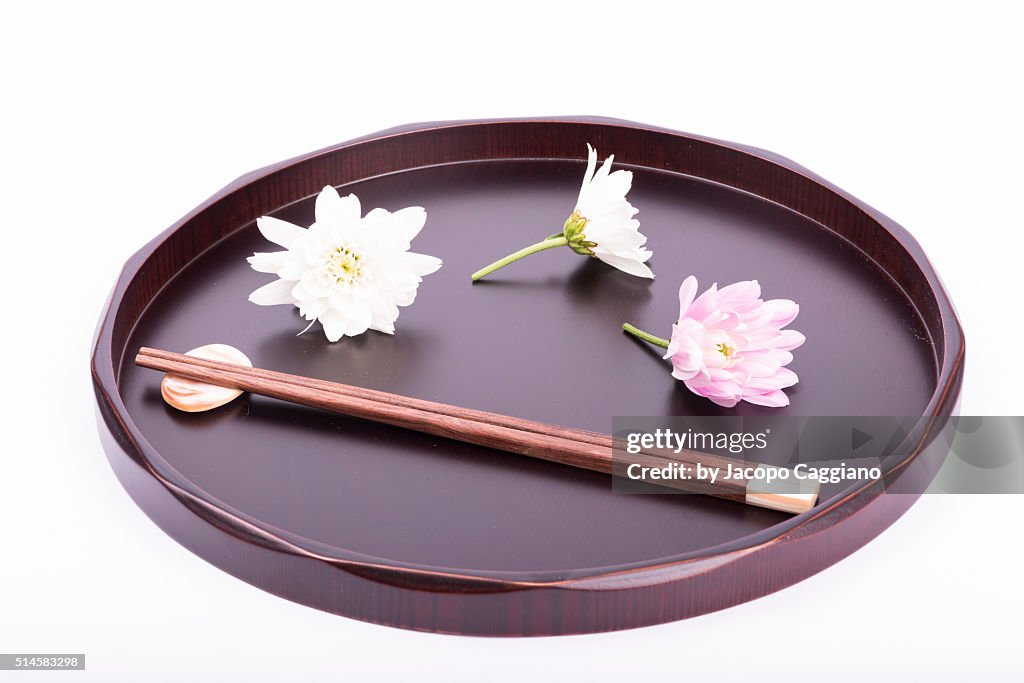 Japanese composition with chopsticks and flowers on a serving plate