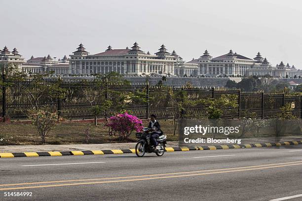 Motorcyclist drives down a road as the Assembly of the Union complex, which houses the upper and lower houses of Myanmar's parliament, stands in the...