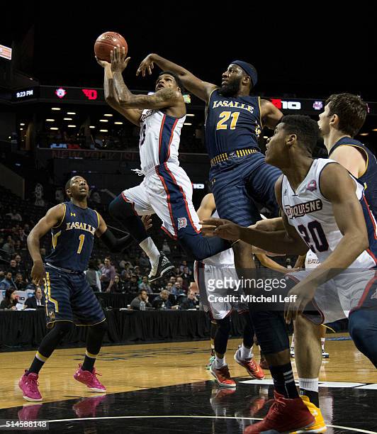 Mar'Qywell Jackson of the Duquesne Dukes attempts a shot against Jordan Price of the La Salle Explorers in the first round of the men's Atlantic 10...