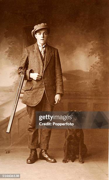 Vintage postcard featuring a studio portrait of a young huntsman with his rifle and labrador, circa 1910.