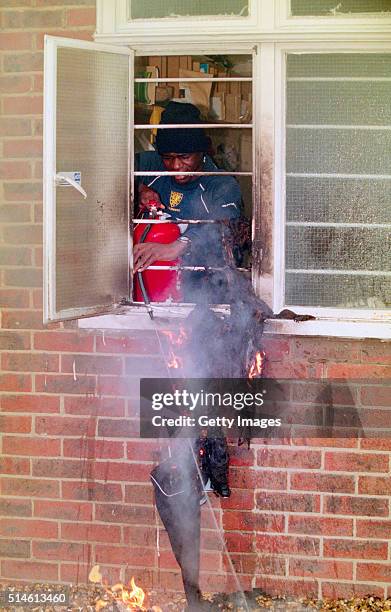 Wimbledon player Robbie Earle uses a fire extinguisher to put out the flames on new signing John Hartson's Armani suit at the clubs training ground...