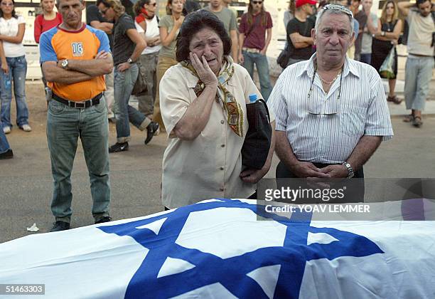 Family members of Rotem Moriah mourn next to his Israeli flag-draped body during his funeral at a Tel Aviv cemetery 11 October 2004. Moriah was one...