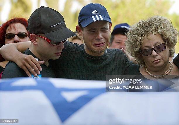 Unidentified relatives of Assaf Greenveld mourn next to his Israeli flag-draped body 11 October 2004 during his funeral at a cemetery in Tel Aviv....