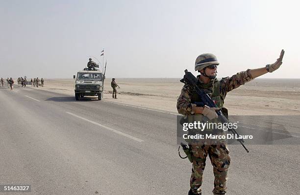 An Italian marine from the Italian Joint Task Force Iraq, San Marco Regiment, holds up a vehicle at a check point on the Tampa road from Basrah to...