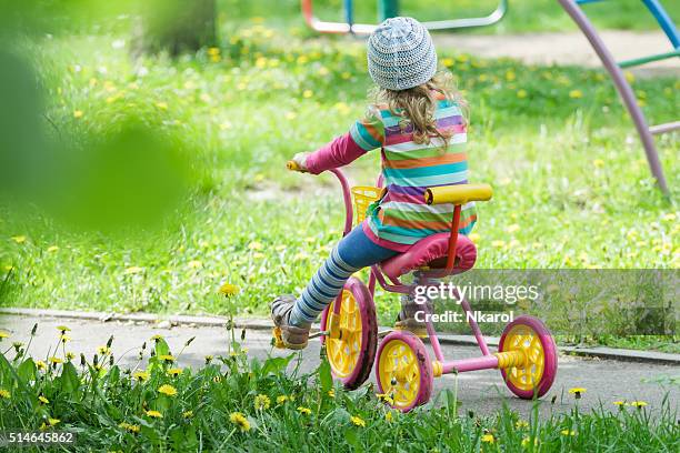 Full length portrait of preschooler girl riding kids tricycle