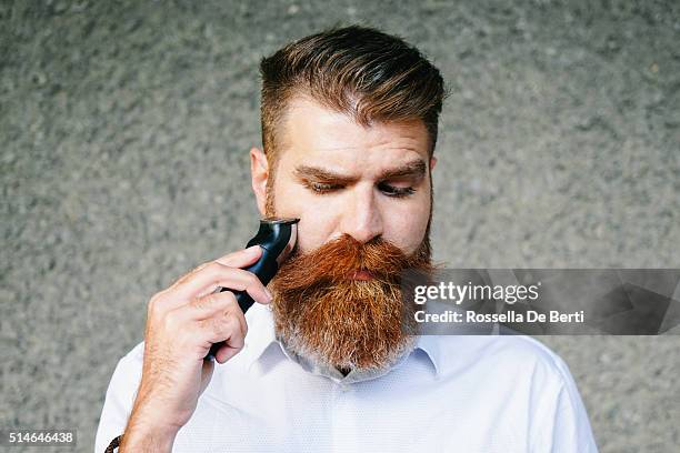 porträt des bärtigen mannes schneiden seinen bart - facial hair stock-fotos und bilder