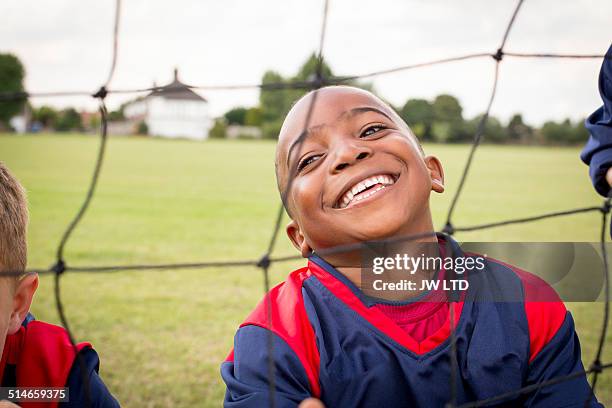 boy behind football goal smiling - smiley stock pictures, royalty-free photos & images