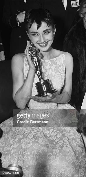 New York, NY: Audrey cuddles up to "Oscar." Audrey Hepburn, who rushed from her hit Broadway play, "Ondine" to receive the Academy Award as "Best...