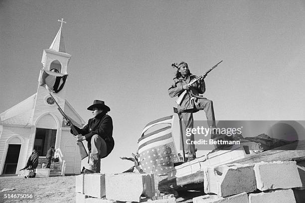 Members of the American Indian Movement and local Oglala Sioux stand guard outside the Sacred Heart Catholic Church after taking control of the town...