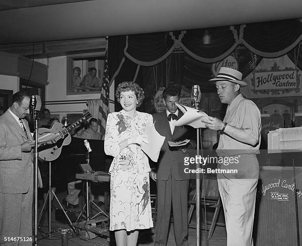 Hollywood, CA.: While Claudette Colbert grins offstage at someone, crooner Frank Sinatra glowers at his "opposition"--Bing Crosby who gives out over...