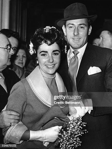 London, England: Glamorous Elizabeth Taylor and British film actor Michael Wilding prepare to leave Caxton Hall Register Office in London, after they...