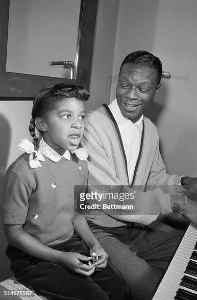 Hollywood, CA: Singer Nat Cole spends his spare time teaching his 7-year-old daughter, "Sweetie," to play the piano, giving her voice lessons at the...