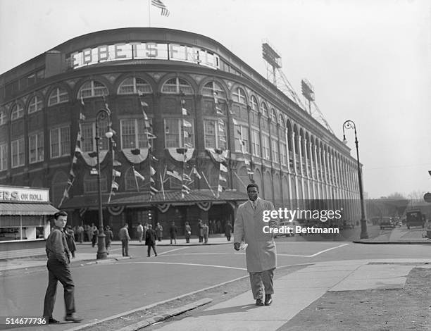 Brooklyn Dodgers baseball star Jackie Robinson walks on the sidewalk across the street from Ebbets Field, the Dodgers' home field. Robinson breaks...