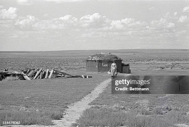 Navajo woman walks towards her hogan, or earth-covered dwelling, on open scrubland on the Navajo Indian Reservation between Chinle and Ganado,...