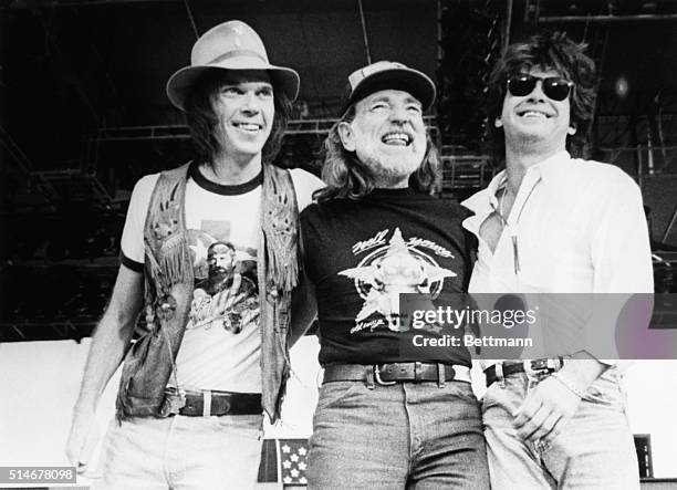 Singer-songwriters Neil Young, Willie Nelson, and John Mellencamp stand together on stage during the 1985 Farm Aid.