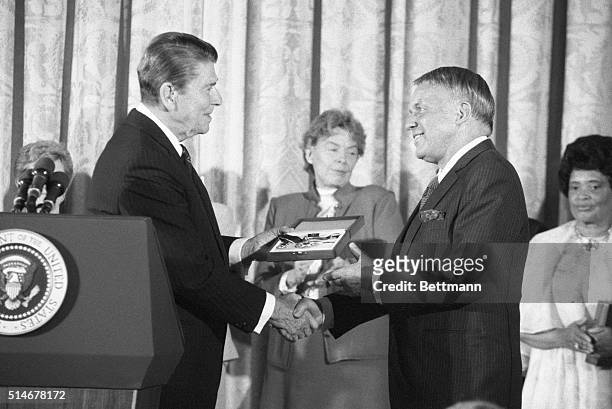 President Ronald Reagan awards the Medal of Freedom to singer Frank Sinatra. Former United Nations ambassador Jeane Kirkpatrick applauds behind them.