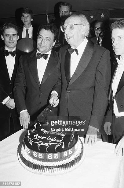 Conductor Zubin Mehta assists composer Aaron Copland in cutting a cake for Copland's 85th birthday gala at Avery Fisher Hall.